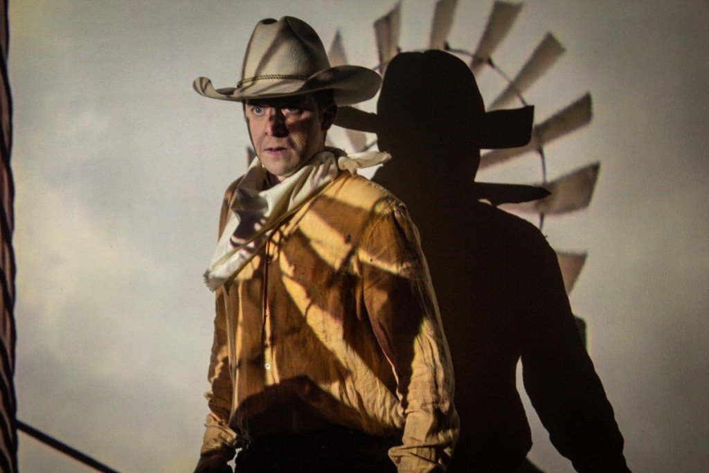 Christopher Sykes in a cowboy costume under theatrical lighting