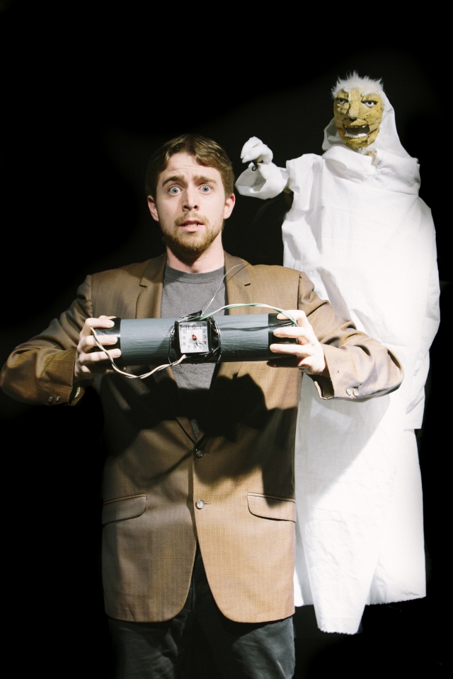 Christopher Sykes performing in a suit beside a white puppet character